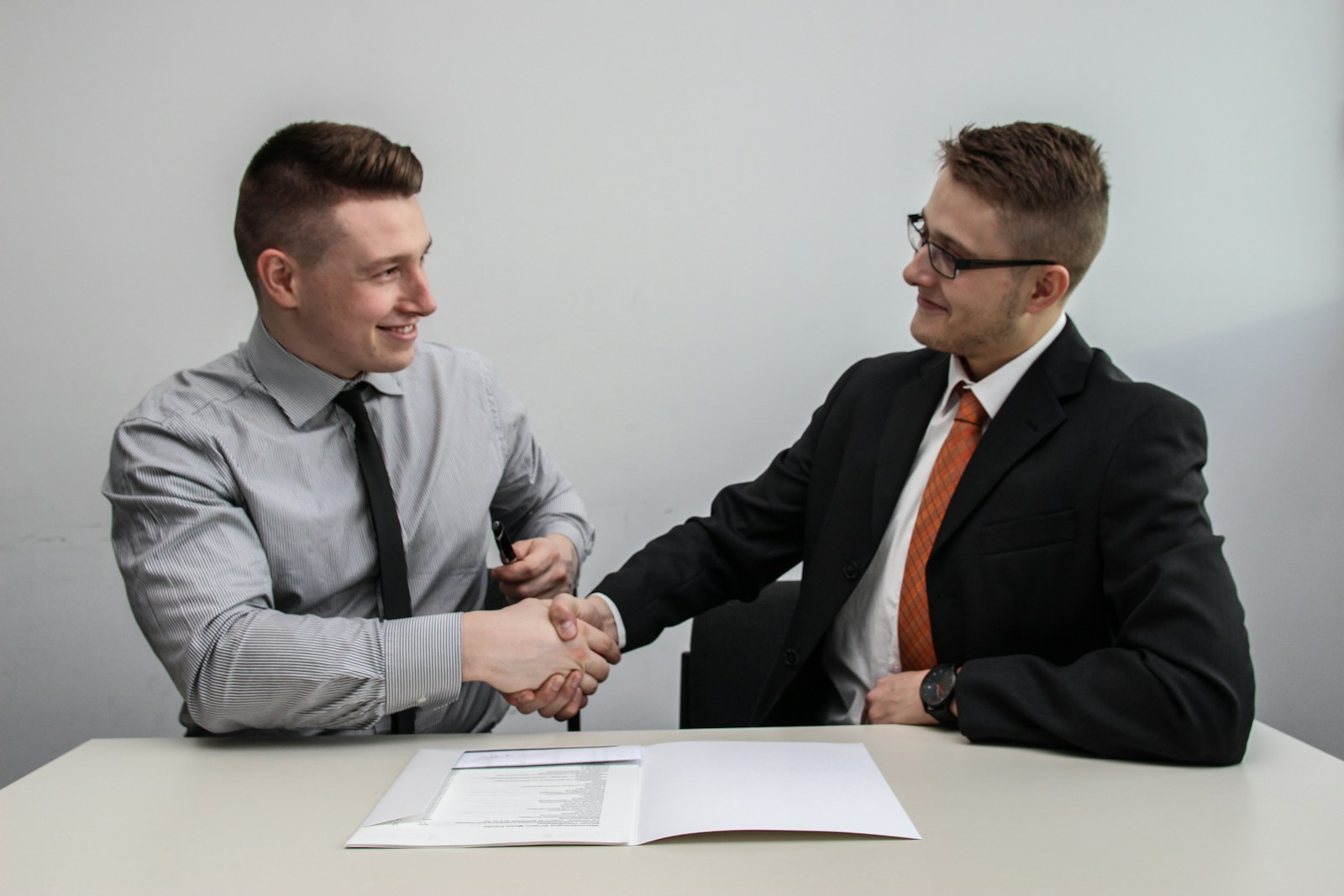 two men facing each other while shake hands and smiling as they dispell myths about employee benefits