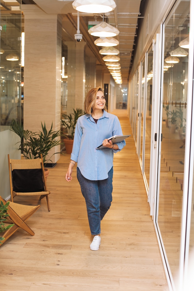 woman with employee benefits in blue dress shirt and blue denim jeans standing beside brown wooden chair